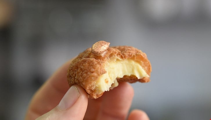 Une main qui tient un petit chou au fromage avec une graine de courgé dorée