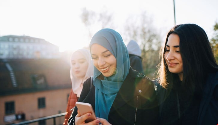 Two young girls looking to a mobile screen.